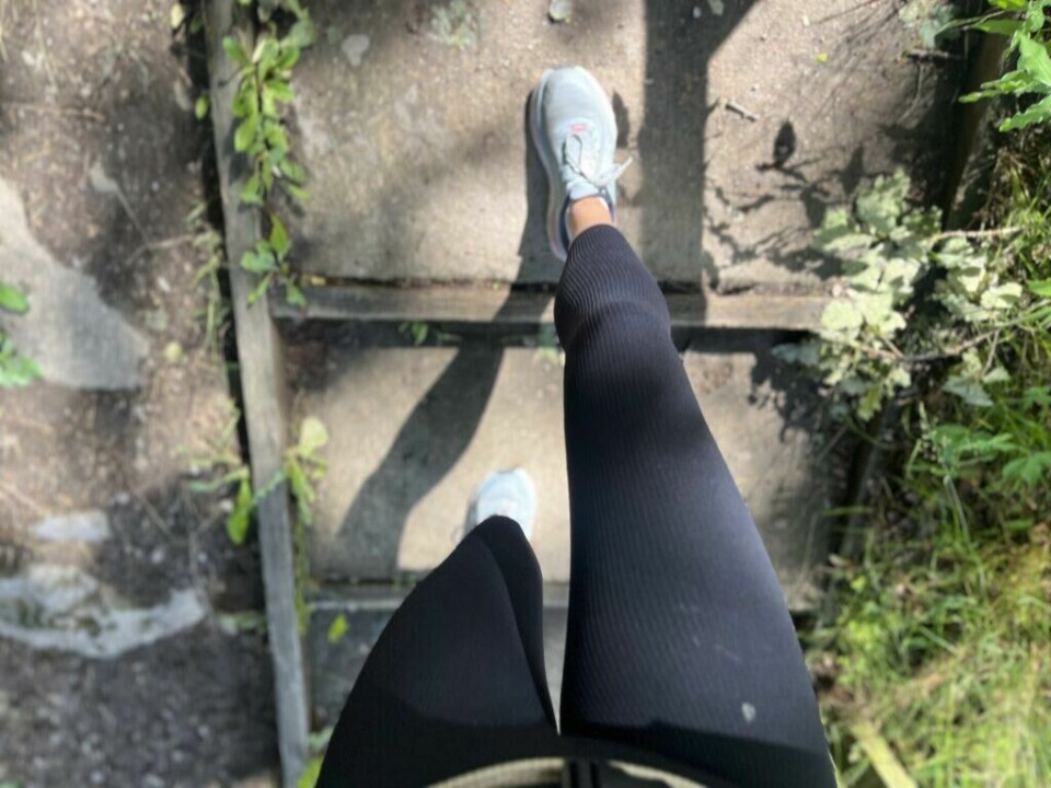 (Foto: Cecilie Aasland / ABC Startsiden) Et bilde tatt ovenfra viser en person som går ned en gammel, slitt utendørs trapp av betong med metallramme. Personen har på seg svarte tights og lyse joggesko. Trappen er omkranset av grønt løv og skygger fra vegetasjonen rundt, og sollyset skaper kontraster på trinnene. Bildet formidler bevegelse, hverdagsaktivitet og kanskje en del av en treningsøkt eller tur i naturen. Styrketrening eller cardio for en strammere og slankere kropp, og flest mulig treningstimer for best resultat? PT-en avkrefter treningsmyter.