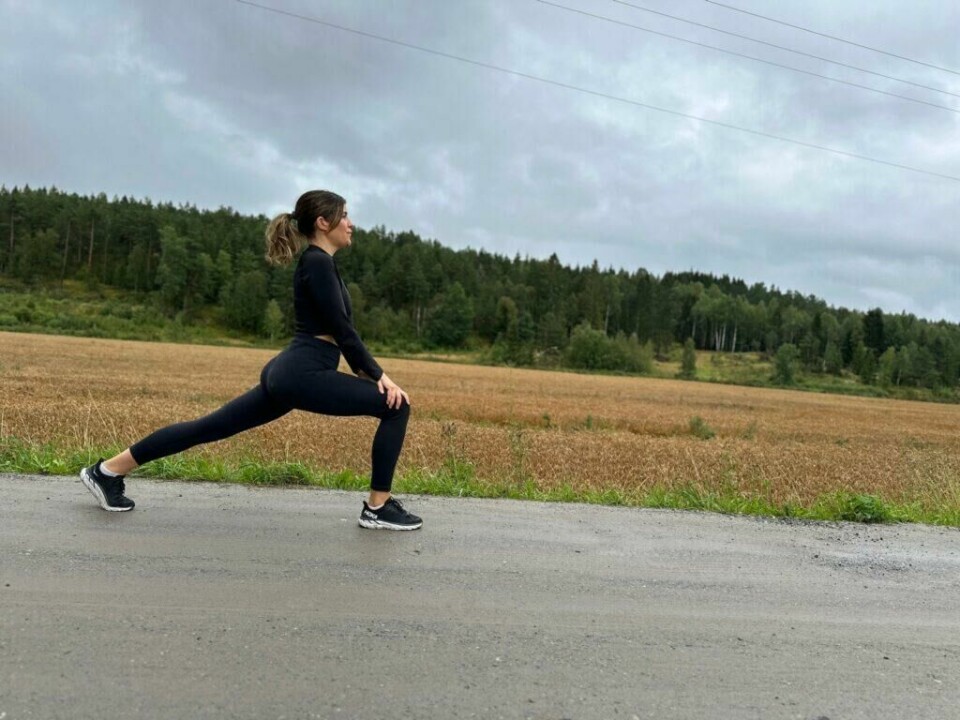 Legger du inn øvelse på øvelse og mye tid på mageøvelser i håp om en stram og fin kropp og en flat mage? PT Cornelis elander forteller om elementet mange ikke vet om som kan ødelegge for både sixpack og resultater fra treningen. (Foto: Mari-Ann Greiner Green) En kvinne kledd i helsvart treningstøy står i en utfallsposisjon (lunge stretch) på en grusvei ved siden av et gyllent kornfelt. Hun ser rolig og fokusert ut, med blikket vendt rett frem. Himmelen er overskyet, og skogen i bakgrunnen rammer inn landskapet. Bildet formidler en følelse av balanse, styrke og tilstedeværelse i naturen – kanskje som en del av oppvarming eller restitusjon etter en løpetur. Styrketrening eller cardio for en strammere og slankere kropp, og flest mulig treningstimer for best resultat? PT-en avkrefter treningsmyter.