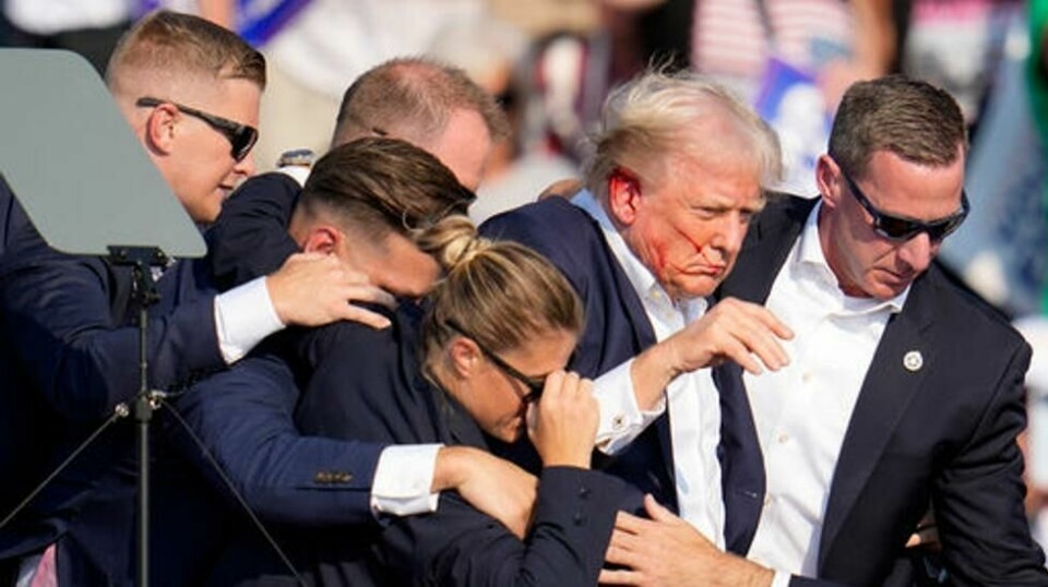 Tidligere president Donald Trump ble skutt i øret under et valgkampmøte i Pennsylvania lørdag. Her blir han beskyttet av Secret Service, som fører ham i sikkerhet. Foto: Gene J. Puskar / AP / NTB