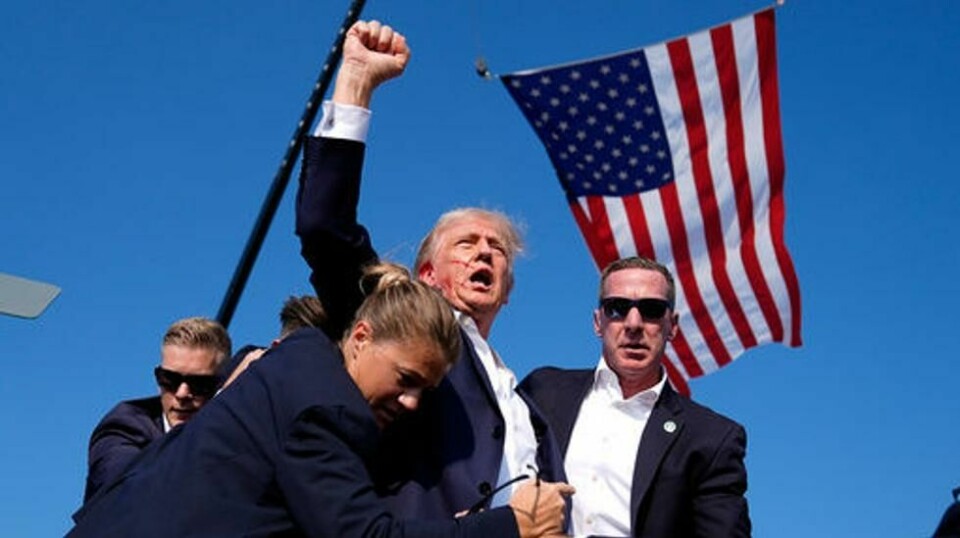 Donald Trump ble tatt hånd om av sikkerhetsvakter idet han reiste en knyttet neve til værs. På bildet kan man se blod fra hans høyre øre. Foto: Evan Vucci / AP / NTB