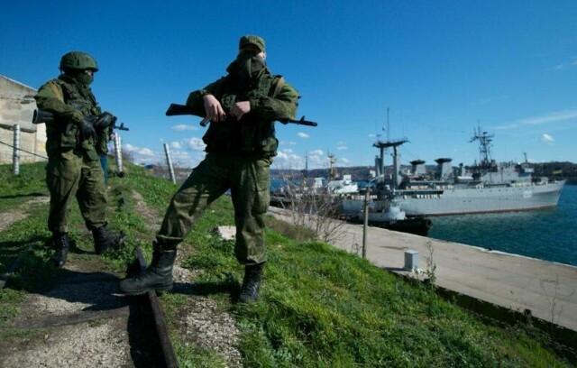 Russiske soldater under anneksjonen av Krim i 2014. De holder vakt over to ukrainske marinefartøy. Eksperter mener at den internasjonale verdensorden slik vi kjenner den fra etter krigen, går i stykker dersom Russland får lov å krige til seg territorium i Ukraina. Foto: AP/NTB