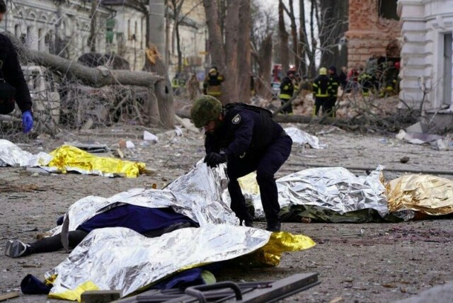 Et bilde gitt ut av ukrainske nødetater viser en politimann som undersøker et av ofrene etter angrepet mot Sumy i Ukraina palmesøndag. Minst 34 ble drept.