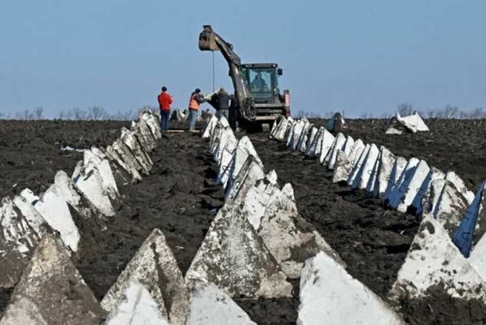 Ukrainske arbeidere installerer panservern, også kjent som dragetenner, på byggeplassen til en forsvarslinje i Kharkiv-regionen 12. mars 2024, under den russiske invasjonen av Ukraina. De baltiske land har planer om å bygge tilsvarende forsvarsverk enkelte steder langs grensen til Russland. (Foto: Sergey BOBOK / AFP) Ukrainske arbeidere installerer panservern, også kjent som dragetenner, på byggeplassen til en forsvarslinje i Kharkiv-regionen 12. mars 2024, under den russiske invasjonen av Ukraina. De baltiske land har planer om å bygge tilsvarende forsvarsverk enkelte steder langs grensen til Russland. (Foto: Sergey BOBOK / AFP) Foto: Sergey Bobok/NTB