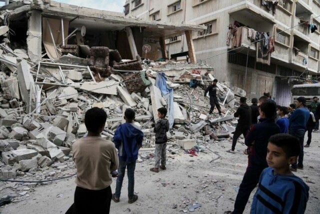 Palestinere ser på ruinene av det sammenraste huset i Gaza by som lørdag ble rammet av et israelsk luftangrep.