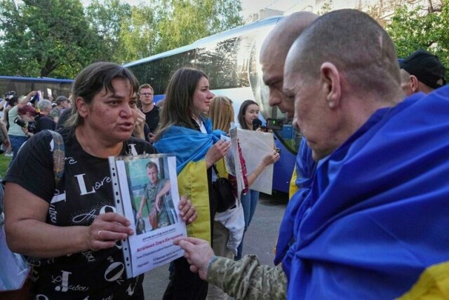 Ukrainere som savner familiemedlemmer, viser bilder av dem til løslatte ukrainske krigsfanger som er kommet tilbake til hjemlandet i forbindelse med fangeutvekslingen fredag.