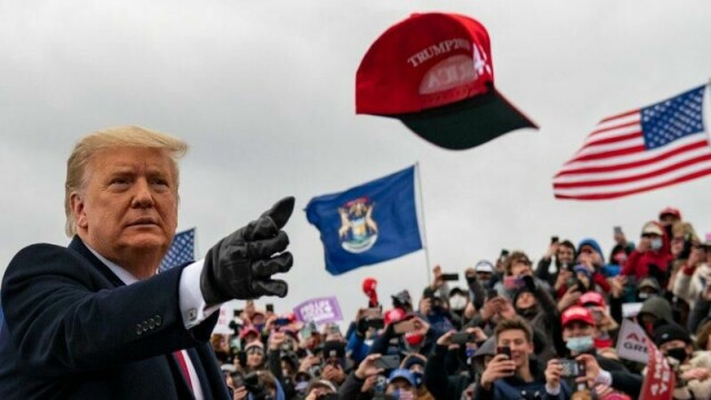 President Donald Trump kaster en caps mot publikum.