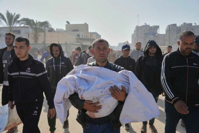 En palestinsk mann bærer liket av nevøen som ble drept i et israelsk angrep i Khan Younis. Lørdag ble gutten gravlagt, og dette bildet ble tatt i den anledning.