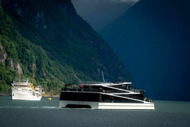 Passasjerkatamaranen Future of the Fjords passerer kongeskipet Norge ved Aurlandsfjorden på dette bildet fra juni 2021. Ferja har gått i turisttrafikk mellom Flom og Gudvangen. Nå er rederiet som bygde ferja, konkurs. Arkivfoto: Heiko Junge / NTB
