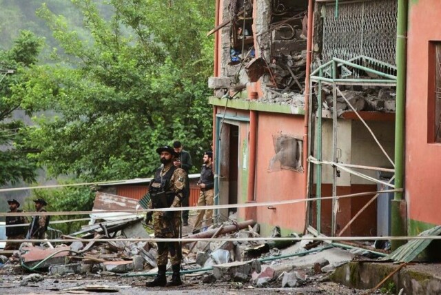 En pakistansk soldat vokter et hus som ble angrepet.