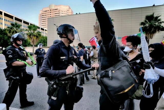 En politimann i Los Angeles dytter tilbake en demonstrant på en gate nær en føderal bygning i sentrum av storbyen.