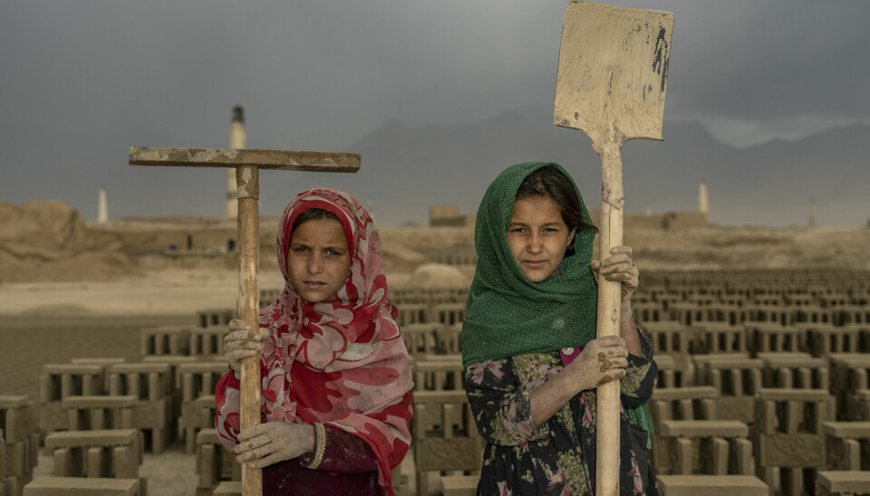 TO afghanske jenter poserer for fotografen på en mursteinsfabrikk utenfor Afghanistans hovedstad Kabul i 2022.