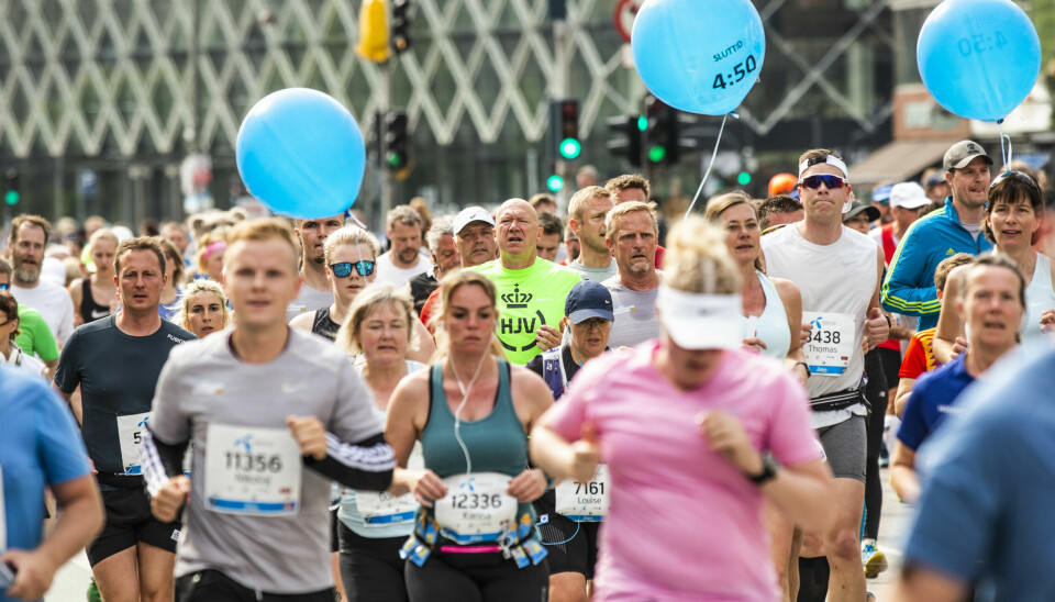 Løpebølgen herjer og maraton verden over er utsolgt i rekordfart. Professor i fysiologi ved UiO Linda Hildegard Bergersen, sier at hun ville ikke turt å løpe maraton flere ganger enn én gang i året etter å ha lest hva som skjer med hjernen under det lange løpet. Bildet viser et stort felt av løpere som deltar i et maraton eller et større gateløp i en urban setting. Deltakerne er i ulike aldre og kjønn, og mange har startnumre festet på brystet. Noen har også løpebelter og ørepropper. I mengden sees to store blå ballonger med teksten 'SLUTTID 4:50', som indikerer fartsholdere for sluttid på 4 timer og 50 minutter. Deltakerne ser fokuserte og anstrengte ut, mens noen smiler. I bakgrunnen skimtes bygninger med glassfasader og trafikklys, som forsterker følelsen av et løp gjennom en bygate.