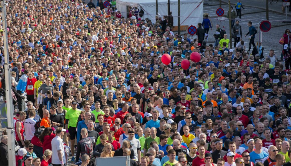 Rekordmange nordmenn er påmeldt avbildede København maraton i 2025. Bildet viser en enorm folkemengde av maratondeltakere samlet før eller under startskuddet til maraton i København i 2014. Løperne fyller hele bredden og lengden av gaten, og skaper et massivt og tett befolket felt. Deltakerne er kledd i treningstøy i alle slags farger, og mange har startnumre festet på brystet. En gruppe røde ballonger svever over mengden, trolig festet til fartsholdere. I bakgrunnen ses et stort hvitt telt, gjerder og noen få tilskuere og arrangører. Stemningen er forventningsfull og energisk, og bildet formidler både omfanget og entusiasmen knyttet til store løpsarrangementer.
