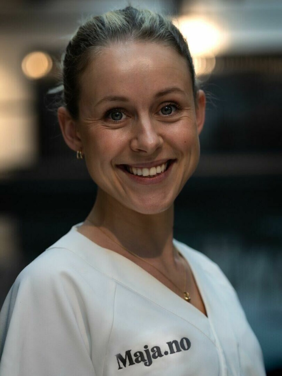 Andrea Birketvedt, medisinsk ansvarlig lege hos Maja.no, forteller at både kjønn, kroppsmasse og sykdommer spiller inn på hvorvidt man fryser lett eller ikke. Bildet viser en kvinne som smiler bredt mot kamera. Hun har på seg en hvit uniform med teksten 'Maja.no' trykt på brystet, som kan indikere at hun jobber for eller representerer dette nettstedet eller firmaet. Hun har oppsatt hår og små, elegante øredobber. Bakgrunnen er uskarp, noe som fremhever hennes ansikt og smil, og skaper en vennlig og profesjonell fremtoning. Vi har snakket med legen som forteller at både kjønn, kroppsmasse og sykdommer spiller inn! Hu forteller også når du bør ta frysingen på alvor.