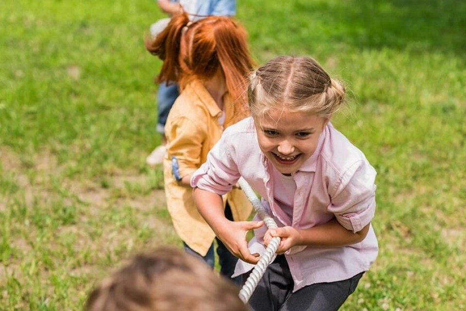 Tautrekking ute i naturen på 17. mai er en lek som engasjerer både store og små. En perfekt lek til 17. mai! (Foto: Colourbox) Bilde av barn som leker selskapsleken tautrekking ute i naturen på grønt gress. En perfekt lek til 17. mai.