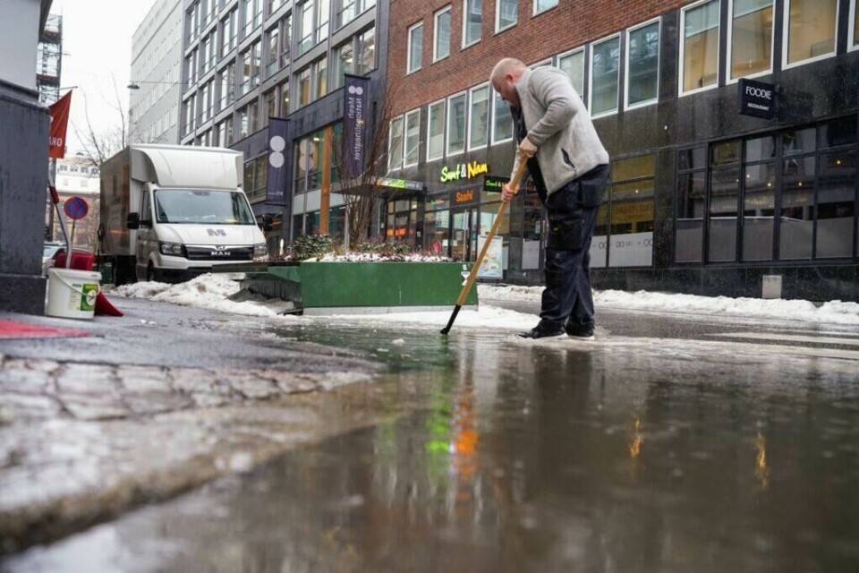 En vaktmester prøver å åpne en tett sluk i Tordenskiolds gate i Oslo. Det er mye overvann på grunn av mildvær, regn og mye snø som smelter. Foto: Ørn E. Borgen / NTB (Foto: Foto: Ørn E. Borgen / NTB)