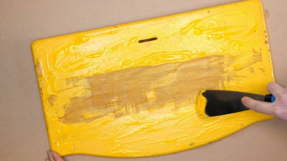 Malingen blir enkel å skrape vekk etter at malingsfjerneren har fått virke. (Foto: ABC Brand Studio) Maling skrapes vekk fra en gul tripptrappstol.