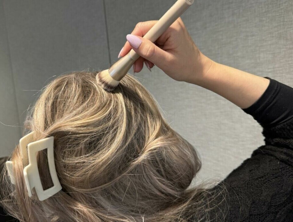 Påføring av potetmel i håret for å fjerne fett og gi volum – en av mange uventede bruksområder. (Foto: Kreative ideer/ Aurora Lange) En person påfører potetmel i hodebunnen med en sminkebørste for å redusere fett og gi håret et friskt, matt utseende. Håret er satt opp med en stor klips, og personen bruker en børste for å påføre potetmelet jevnt. Dette er et uventet bruksområde for potetmel, som vanligvis brukes i matlaging, men som også fungerer som en naturlig tørrsjampo mellom hårvasker