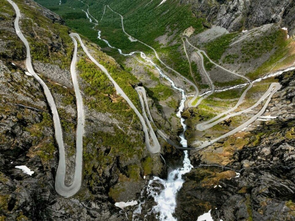 Trollstigen er kanskje stengt i år, men området rundt, samt Geirangerfjorden er fortsatt verdt å få med seg. (Foto: Freysteinn Jonsson/Unsplash) n imponerende luftfoto av Trollstigen, en bratt og svingete vei som slynger seg nedover et fjelllandskap. Veien består av mange skarpe hårnålssvinger og strekker seg over et grønt og steinete terreng. En foss kan sees i midten av bildet, der vannet strømmer nedover fjellsiden. Området er omgitt av frodig vegetasjon og bratte fjell. Her får du tips til syv vakre bilturer i Norge som er perfekt for norgesferien. Geiranger og Trollfjorden, Atlanterhavsveien, Lofoten, Hardanger, Rondane, Gamle Strynefjellsvegen, Senja.