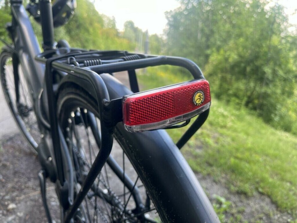 Visste du at du blir enda mindre synlig på sykkel om det regner og veibanen er våt? (Foto: Cecilie Aasland / ABC Startsiden) Bilde av en rød refleks på en svart elsykkel. Elsykkelen står ved en gressplen med et vann i bakgrunnen i sol og sommervær. Vi forteller om reglene du må kjenne til og som går på lys, refleks og lykter på elsykkel. Har du de ikke kan du nemlig få bot!