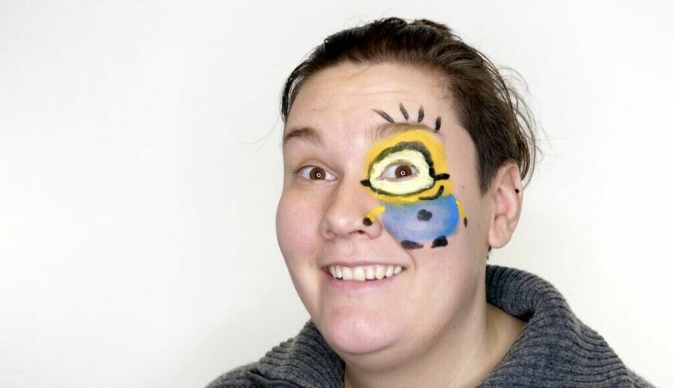 Ta humoren til neste nivå med kreativ Minion-ansiktsmaling! (Foto: Kreative Ideer/ Miriam Schjetlein) Bildet viser en voksen person med ansiktsmaling av en gul Minion-figur. Minionen er malt slik at personens eget øye fungerer som Minionens ene store øye, med svarte briller rundt og resten av figuren under. Personen smiler bredt og har på seg en grå genser. Den enkle, hvite bakgrunnen gjør at den humoristiske ansiktsmalingen står i fokus.