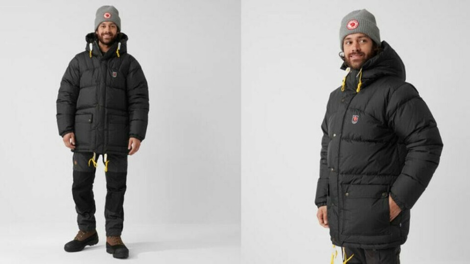 Lang og vel-isolerende dunjakke for virkelig kaldt vinterklima! (Foto: Fjällreven) Bildet viser en mann som har på seg en tykk, varm og polstret vinterjakke fra Fjällräven. Jakken er svart med gule snorer på hetten og nederst, som gir et kontrasterende utseende og mulighet for justering av passformen. Fjällräven-logoen er synlig på venstre side av brystet. Jakken har store lommer og en lengre passform, som gir ekstra beskyttelse mot kulde. Mannen er også kledd i en grå lue med Fjällräven-logoen foran. Jakken ser varm og slitesterk ut, egnet for ekstreme vinterforhold og utendørsaktiviteter.