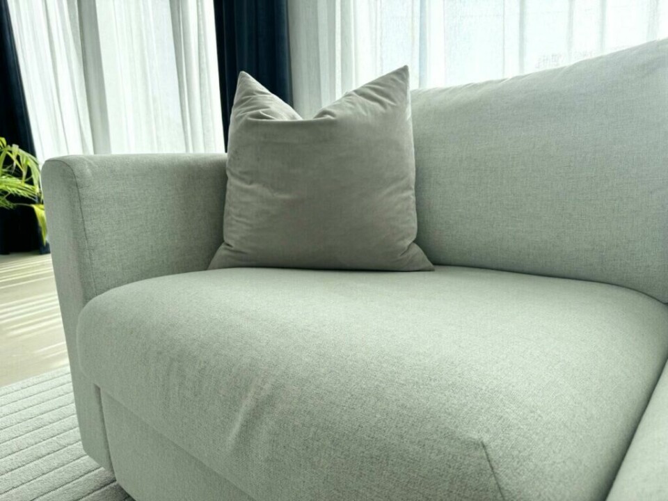 En moderne, minimalistisk sofa med en myk pute i lyse gråtoner, plassert i et stilrent interiør. (Foto: Kreative ideer/ Aurora Lange)