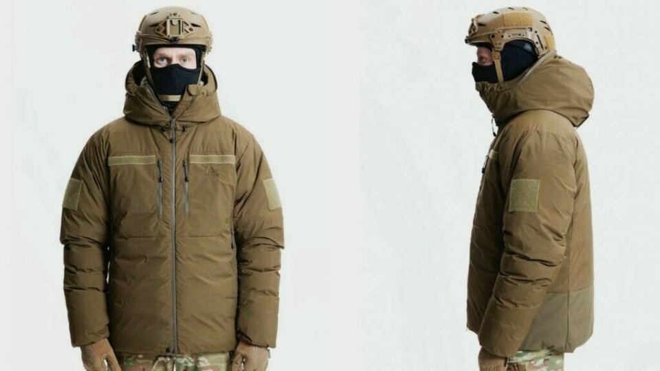 Varm vinterjakke til herre fra Mountain Equipment er også vanntett! (Foto: Milrab) Bildet viser en mann iført en militærinspirert vinterjakke i en olivengrønn farge. Jakken er designet for å være funksjonell i ekstreme værforhold, med en tykk polstring for varmeisolasjon. Den har flere praktiske funksjoner, inkludert brystlommer med glidelås, forsterkede albuepartier og borrelåsfelt på armene, som indikerer mulighet for påsydde merker eller tilpasninger. Mannen har også på seg en taktisk hjelm og en ansiktsmaske, som tyder på at jakken er designet for bruk i krevende, taktiske situasjoner. Jakken har en hette for ekstra beskyttelse, og passformen ser romslig og komfortabel ut, med god bevegelsesfrihet. Designet er robust og slitesterkt, noe som gjør den egnet for utendørs- eller militærbruk i kalde omgivelser.