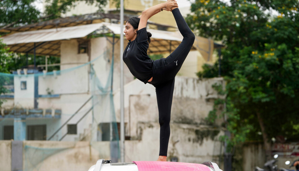 En jente i yogastilling på et biltak i Ahmedabad.