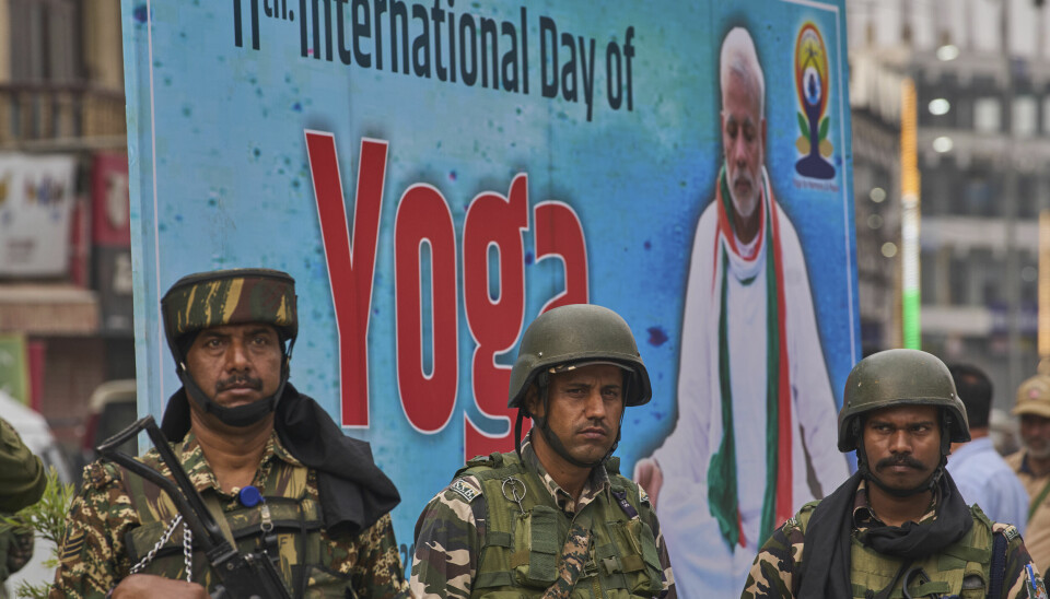 Indiske paramilitære soldater holder vakt mens innbyggere praktiserer yoga i Srinagar i indiskkontrollerte Kashmir.