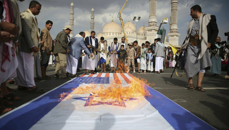Houthi-tilhengere i Jemens hovedstad Sana brenner amerikanske og israelske flagg i en demonstrasjon fredag.