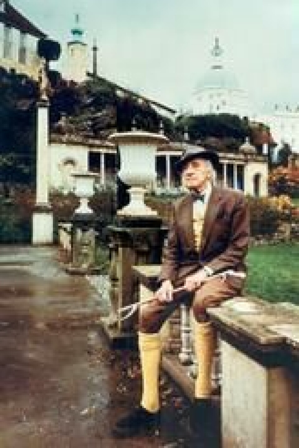Bertram Clough Williams-Ellis i sin kjente uniform: brun tweed-dress og sennepsgule sokker til knærne. Her sitter han på piazzaen i sentrum av Portmeirion. Bertram Clough Williams-Ellis i sin kjente uniform: brun tweed-dress og sennepsgule sokker til knærne. Her sitter han på piazzaen i sentrum av Portmeirion. Foto: Village Portmeirion