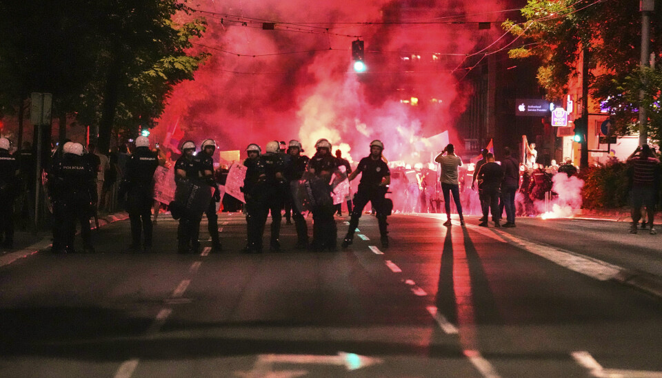 Opprørspoliti stenger en gate hvor demonstranter har kastet lysbluss. Politiet har svart med tåregass mot enkelte av demonstrantene.