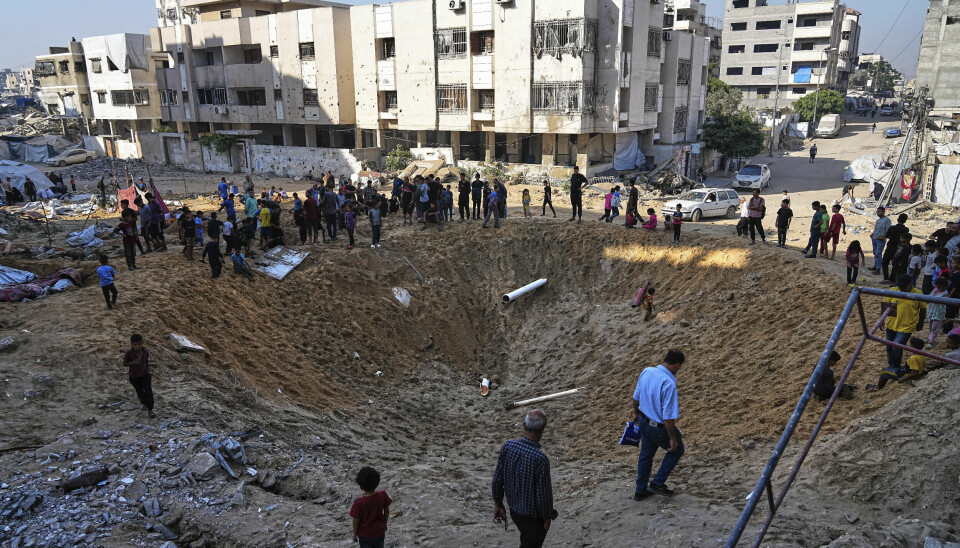 Palestinere ser på bombekrateret etter et israelsk angrep mot telt med internt fordrevne i Gaza by lørdag.