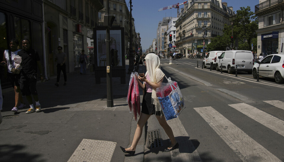 En kvinne beskytter hodet mot de stekende solstrålene i Paris der farevarselet er oppe på rødt nivå.