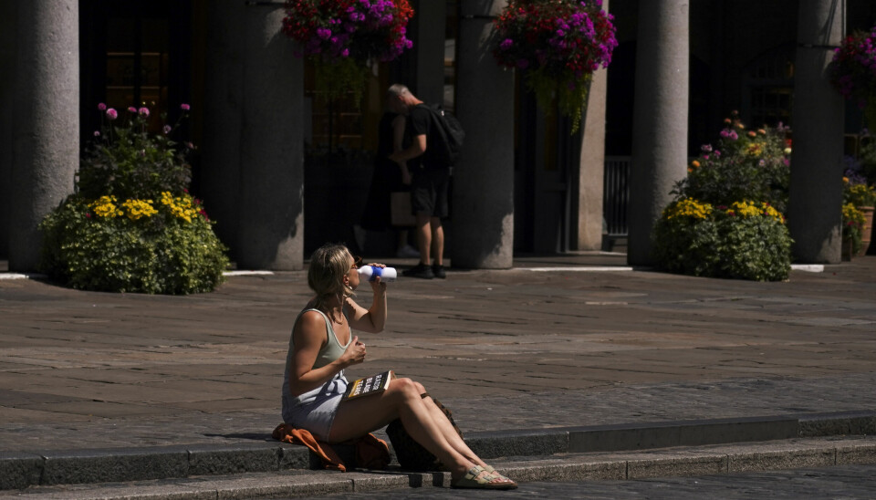 En person tar seg en slurk av en drikke i Covent Garden i London under hetebølgen i England mandag.
