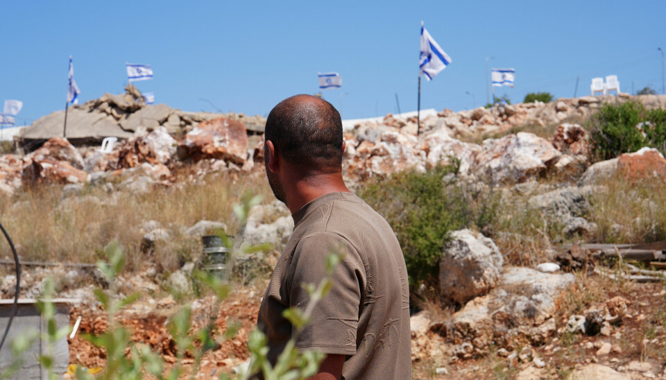 Ein palestinsk mann ser på israelske flagg som er plasserte over eit øydelagt palestinsk hus etter eit åtak frå israelske busetjarar i landsbyen Bruqin nær Salfit.