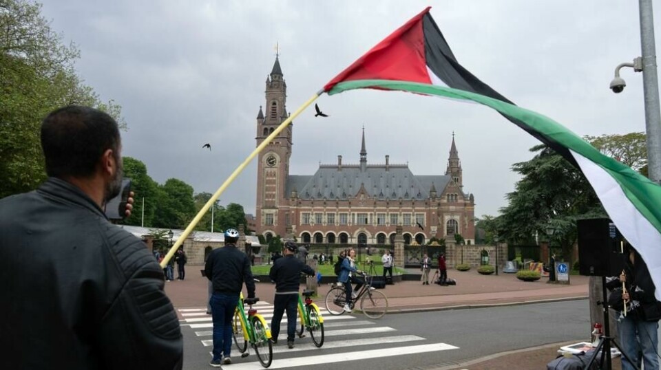 En demonstrant vifter det palestinske flagget utenfor FN-domstolen ICJ i Haag fredag 24. mai, samme dag som domstolen beordret Israel til å stanse angrepene på Rafah.