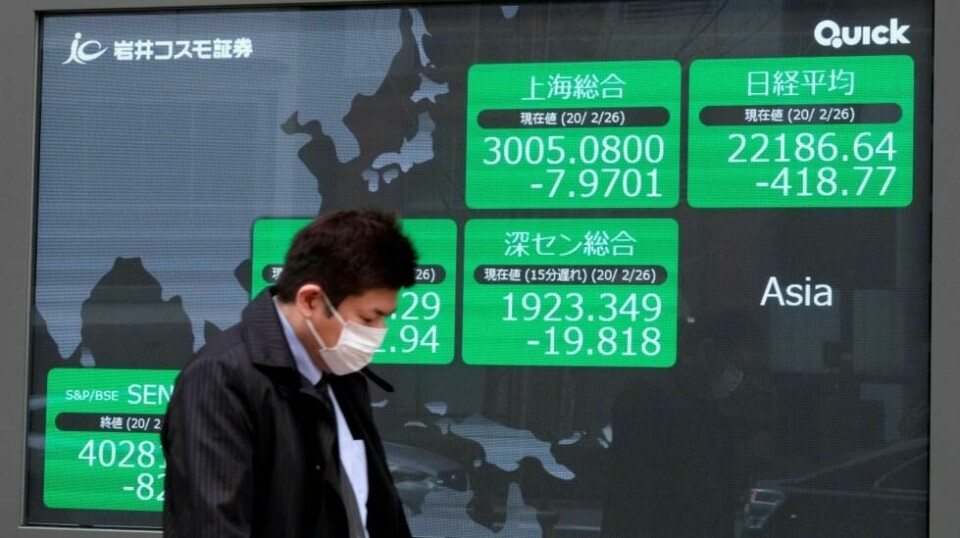 En forbruker passerer en skjerm som viser aksjeprisene på Nikkei 225-indeksen. Også Oslo Børs er hardt rammet av koronakrisen denne uken. NTB Scanpix/AFP.