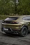 Bakfra vises en gullfarget Lamborghini Urus parkert utendørs, med markante linjer og brede dekk.
Nøkkelord: Lamborghini Urus, SUV, luksusbil.