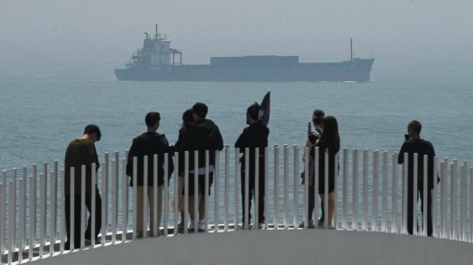 Kinesiske turister kikker utover Taiwanstredet med et frakteskip i bakgrunnen. Bildet er tatt ved øya Pingtan, som er det nærmeste punktet til Taiwan kontrollert av fastlands-Kina.