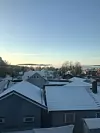 Bilde av eneboliger og leilighetskompleks en solskinnsdag, med blå himmel, sol og snø.