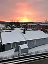 Bilde av eneboliger og leilighetskompleks i solnedgang og snø.