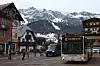 Buss og fotgjenger i sentrum av Cortina d’Ampezzo med snødekte fjell i bakgrunnen.