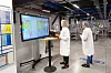To ansatte i hvite frakker studerer en stor skjerm inne i Biomerieuxs produksjonslokale.