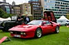 Ferrari 288 GTO utstilt på gressplen med åpent motorlokk og publikum rundt.