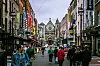 Fotgjengere i travel handlegate med butikker og kirke i enden av gaten i Dublin