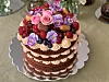Flere lag sjokoladekake med Dumlekrem, bær og blomster på et kakefat.