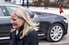 Kronprinsesse Mette-Marit går utendørs foran en svart bil med norsk vognfane.