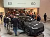 Messepublikum rundt en mørk Volvo EX60 på innendørs bilutstilling. Interessen for den nye Volvo EX60 er meget stor, ikke bare i Norge.